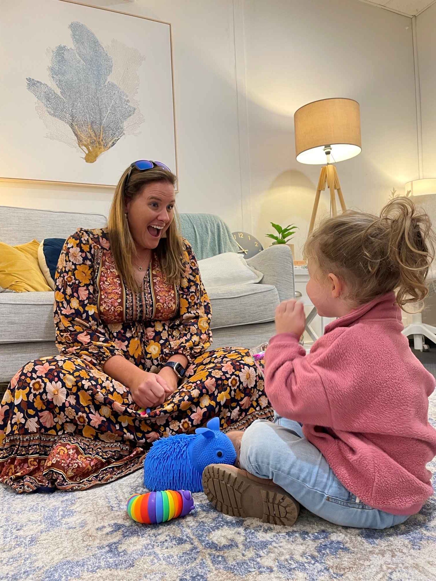 Natalie Jarvis and child sit on ground playing in her autism counselling space in Terrigal. 